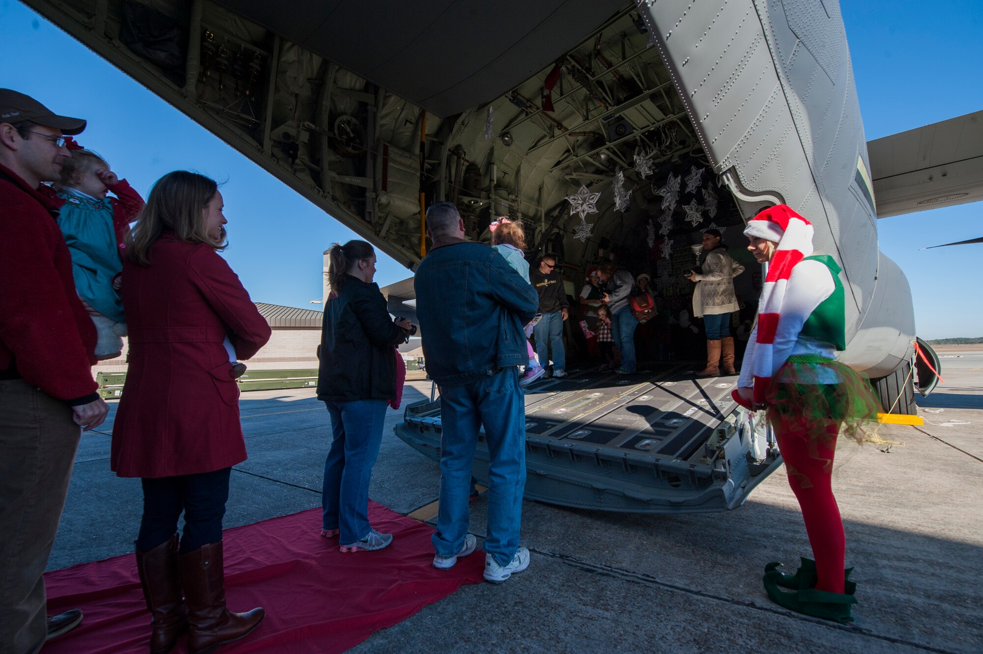 Families wait outside of an HC-130J Combat King II to see Santa Claus during the 23d Maintenance Group and 347th Rescue Group children’s Christmas party Dec. 13, 2014, at Moody Air Force Base, Ga. Santa greeted families inside the C-130 and gave them Christmas gifts. (U.S. Air Force photo by Airman 1st Class Dillian Bamman/Released)
