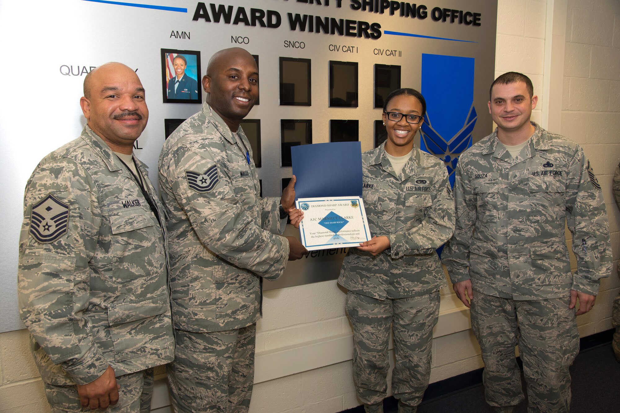 Hanscom first sergeants (left to right) Master Sgt. Kevin Walker, Tech. Sgt. David Walls and Master Sgt. Nicholas Souza present Airman 1st Class Marniece Clarke, a Joint Personal Property Shipping Office storage management technician, the Diamond Sharp Award at JPPSO on Hanscom Air Force Base, Mass. Dec. 15. The first sergeants selected Clarke as the recipient of the award for performance reflecting the highest standard of professionalism and pride. The Diamond Sharp program, adopted by the First Sergeant Council, aims to recognize the base’s sharpest personnel in the grades of Airmen Basic through Tech. Sgt. (U.S. Air Force photo by Mark Herlihy)