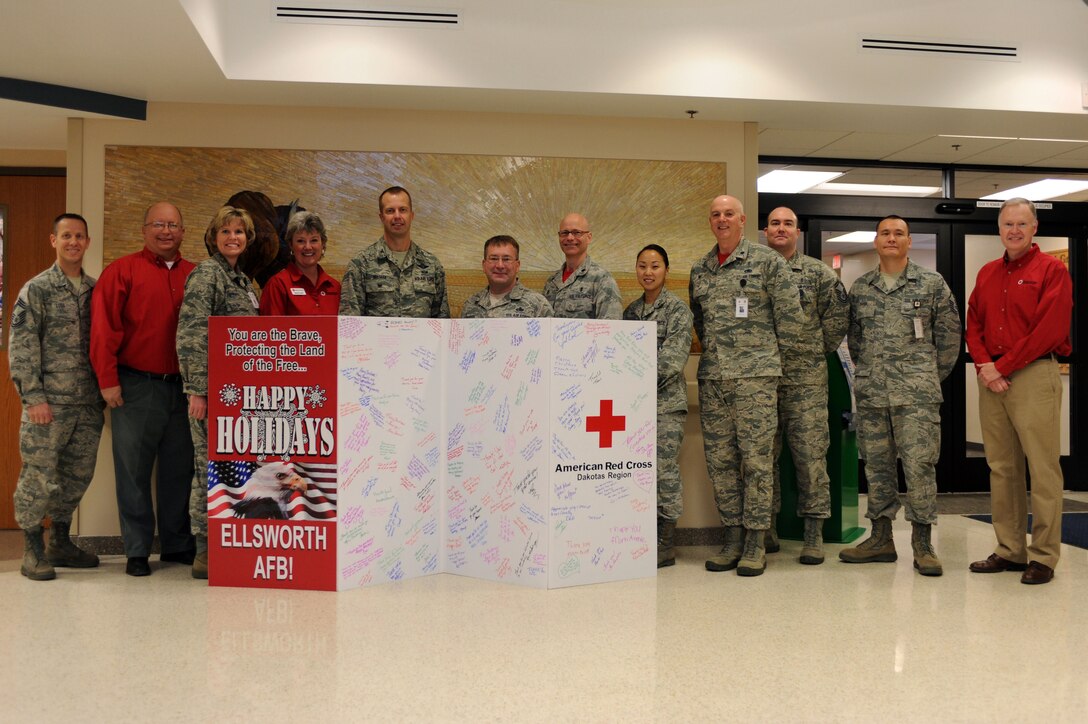Ellsworth leadership and American Red Cross members pose for a group photo with the Red Cross holiday card at the 28th Medical Group at Ellsworth Air Force Base, S.D., Dec. 12, 2014. Each year, the Red Cross reaches out to the surrounding communities to create a holiday greeting card to express their gratitude for servicemembers during the holiday season. (U.S. Air Force photo by Senior Airman Hailey R. Staker/Released) 