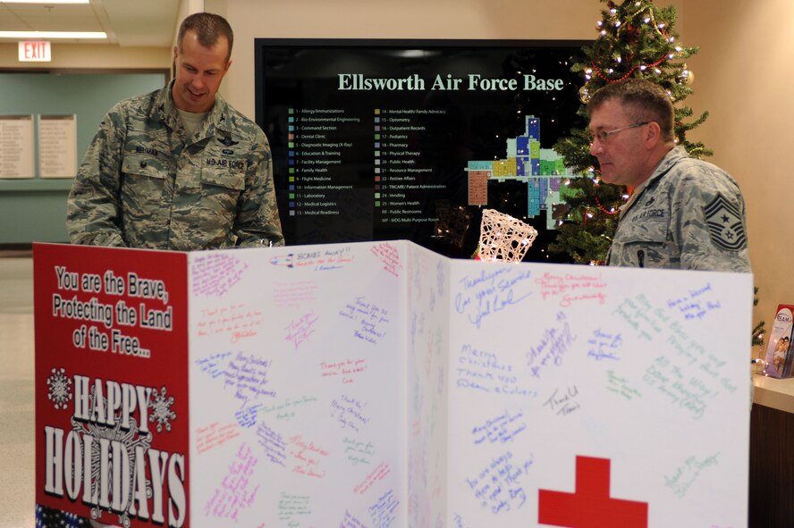 Col. Ty Neuman, 28th Bomb Wing vice commander, and Chief Master Sgt. Kevin Peterson, 28th BW command chief, read holiday greetings from South Dakota and North Dakota community members on a Red Cross holiday card at the 28th Medical Group at Ellsworth Air Force Base, S.D., Dec. 12, 2014. The Red Cross passed around the card to various communities throughout the states to collect messages of their gratitude to the troops during the holiday season. (U.S. Air Force photo by Senior Airman Hailey R. Staker/Released)