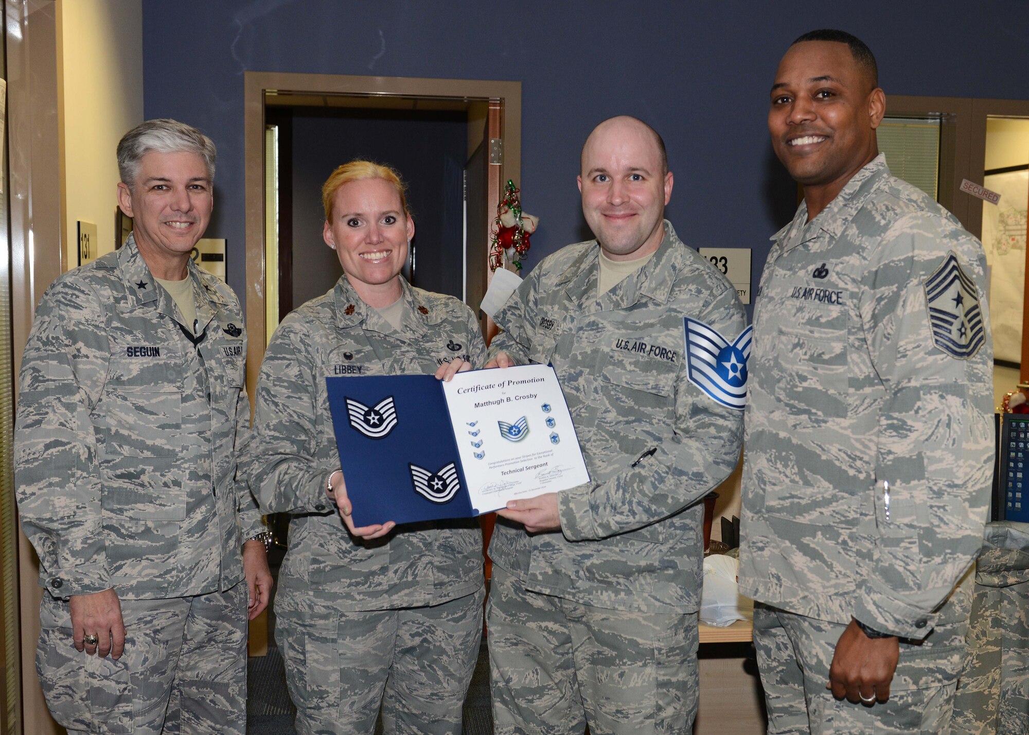 Brig. Gen. Barre Seguin, 31st Fighter Wing commander, Maj. Michelle Libby, 31st Comptroller Squadron commander and Chief Master Sgt. Anthony Johnson, 31st Fighter Wing command chief present Tech. Sgt. Matthugh Crosby, 31st Fighter Wing ground safety technician, a certificate for his promotion to technical sergeant through the Stripes for Exceptional Performers program, Dec. 15, 2014, at Aviano Air Base, Italy. Each year wing commanders are given the opportunity to promote one of their brightest through this program. (U.S. Air Force photo/Airman 1st Class Deana Heitzman)