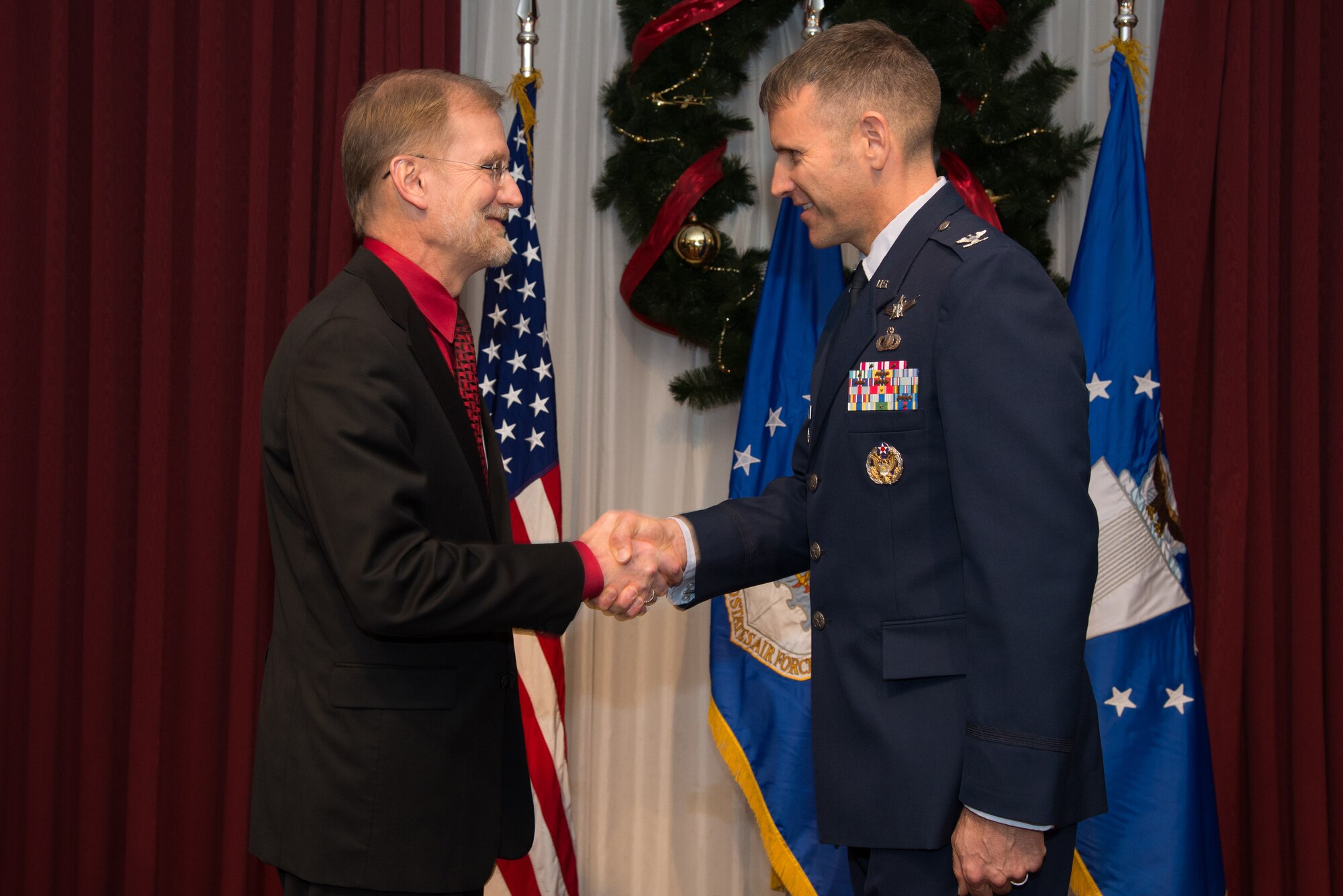 Steven Wert, Battle Management program executive officer, shakes hands with U.S. Air Force Col. David Learned, the first JSTARS Recapitalization Division senior materiel leader, during the JSTARS Recap Division stand-up ceremony at Hanscom AFB, Mass., Dec. 5, 2014. The Recap, which is the service's fourth largetst acquisition priority, is focused on replacing the aging fleet of E-8C aircraft that is used to detect tarets at long distances. The program's size and significance has grown resulting in its own Battle Management division at Hanscom. (U.S. Air Force photo by Mark Herlihy)