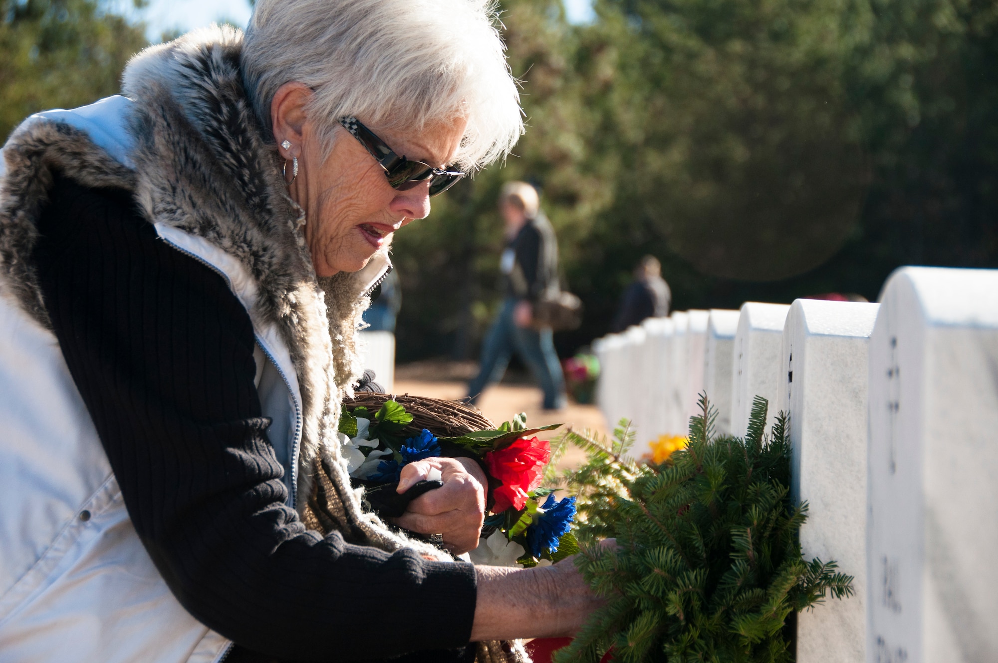 A volunteer lays a wreath on a gravestone for Wreaths Across America at Georgia National Cemetery in Canton, Ga. Dec. 13, 2014. Wreaths Across America occurs the second Saturday of December every year. (U.S. Air Force photo/Senior Airman Daniel Phelps)