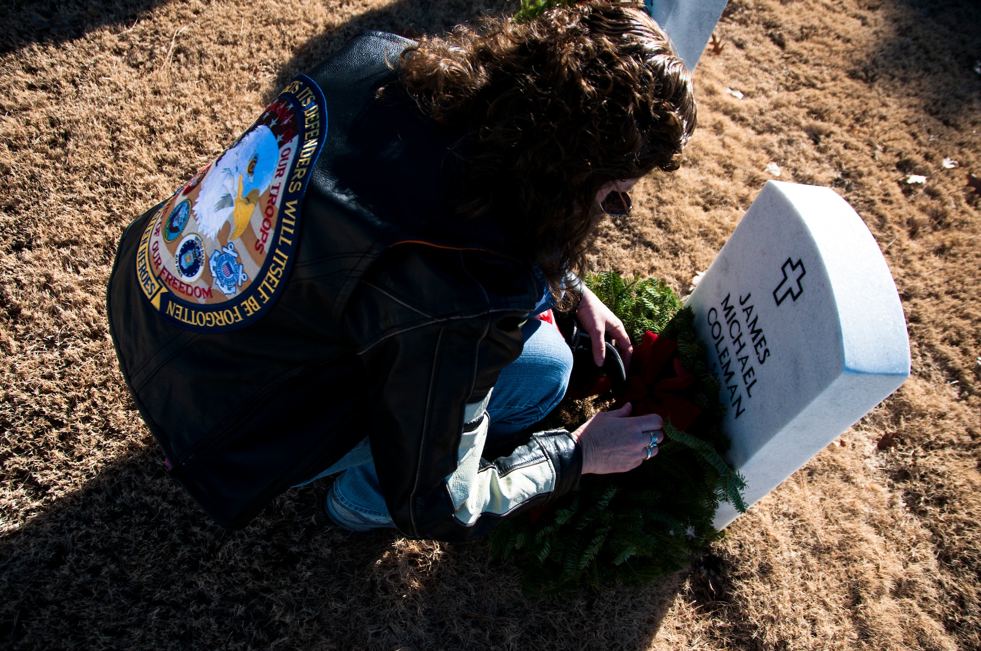 A volunteer lays a wreath on a gravestone for Wreaths Across America at Georgia National Cemetery in Canton, Ga. Dec. 13, 2014. Wreaths Across America occurs the second Saturday of December every year. (U.S. Air Force photo/Senior Airman Daniel Phelps)