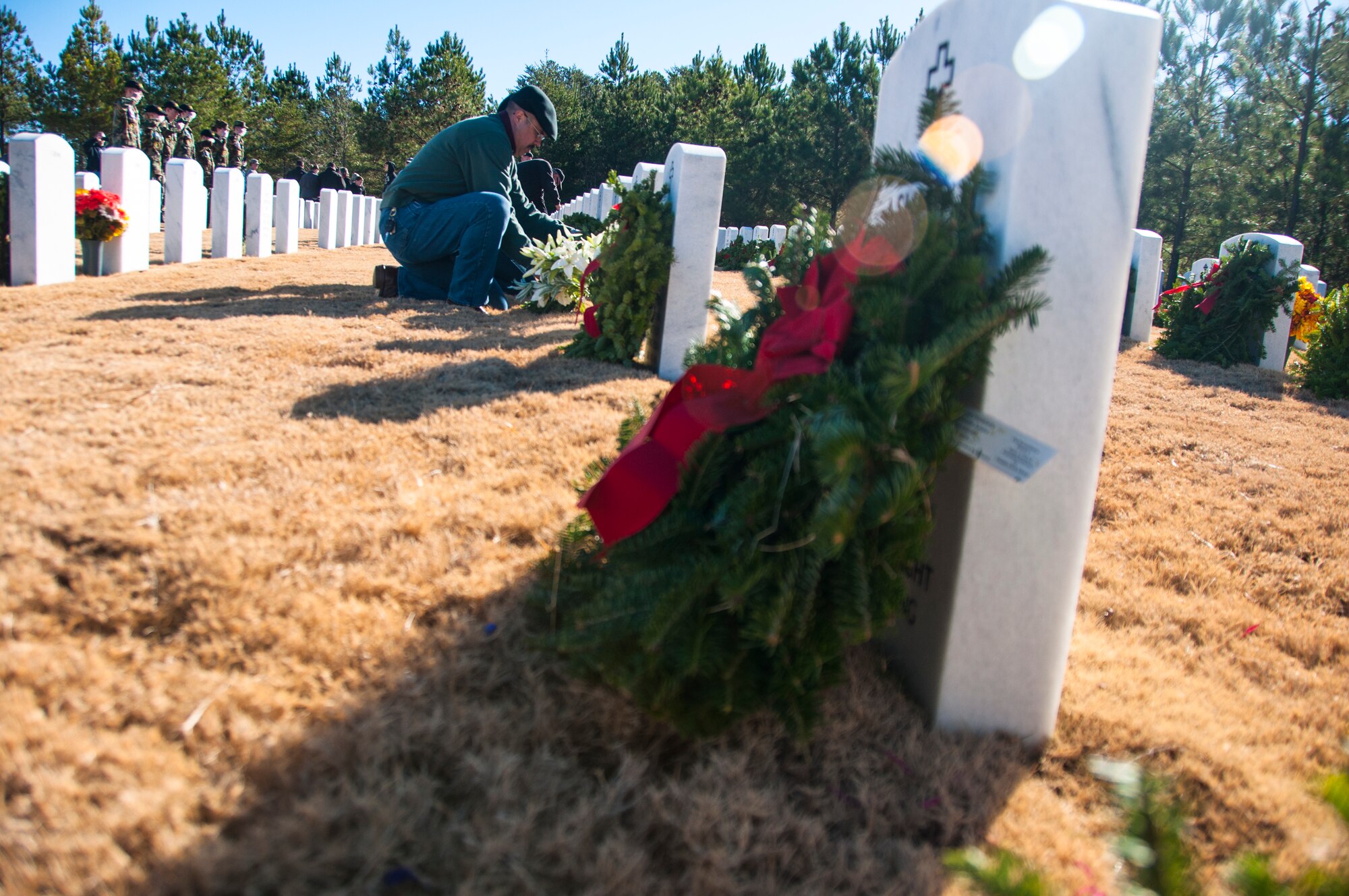 A volunteer lays a wreath on a gravestone for Wreaths Across America at Georgia National Cemetery in Canton, Ga. Dec. 13, 2014. Wreaths Across America occurs the second Saturday of December every year. (U.S. Air Force photo/Senior Airman Daniel Phelps)