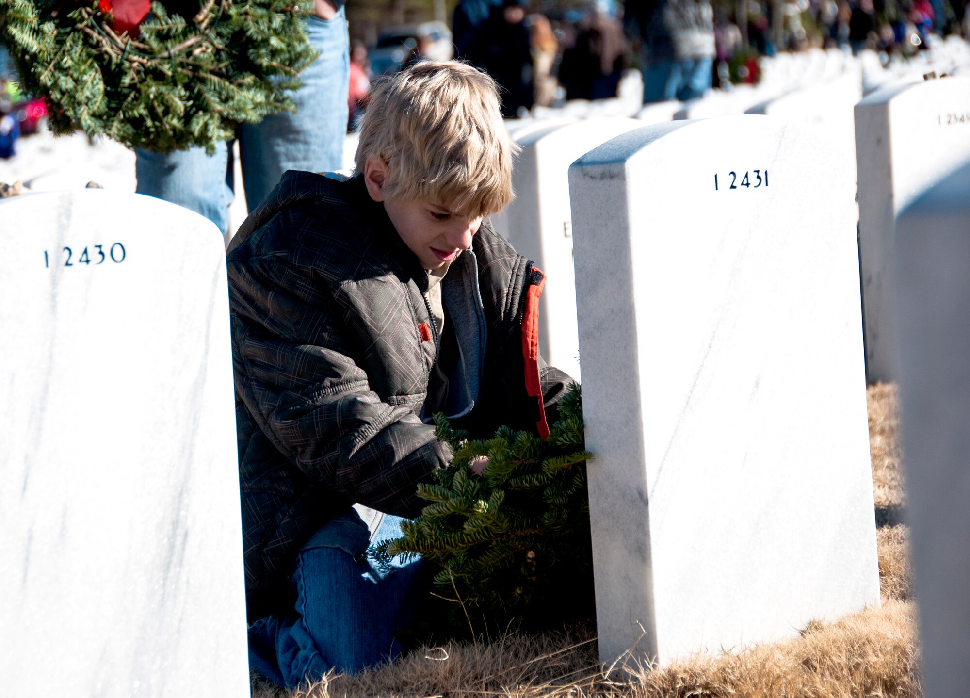 A volunteer lays a wreath on a gravestone for Wreaths Across America at Georgia National Cemetery in Canton, Ga. Dec. 13, 2014. Wreaths Across America occurs the second Saturday of December every year. (U.S. Air Force photo/Senior Airman Daniel Phelps)