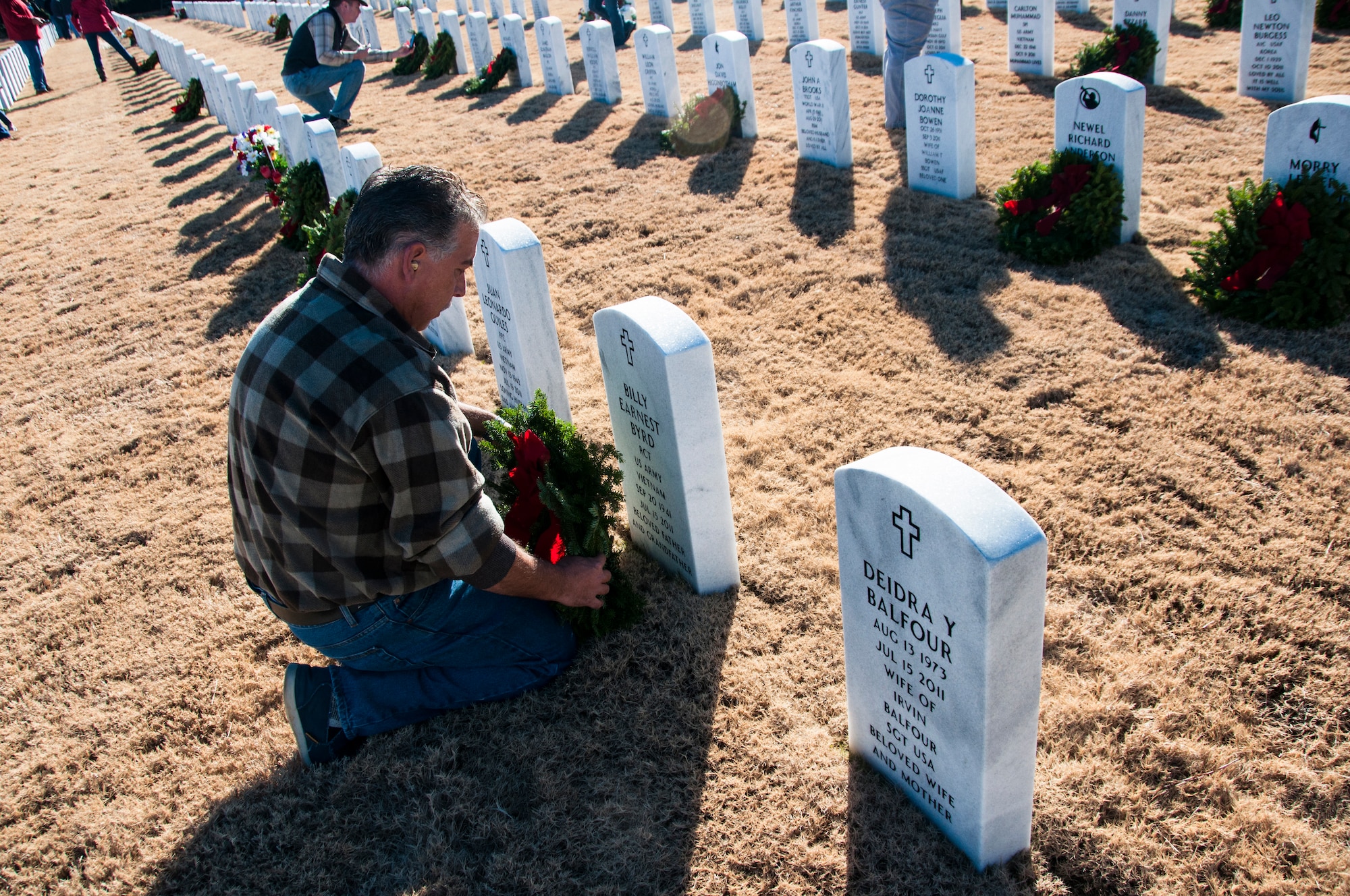 A volunteer lays a wreath on a gravestone for Wreaths Across America at Georgia National Cemetery in Canton, Ga. Dec. 13, 2014. Wreaths Across America occurs the second Saturday of December every year. (U.S. Air Force photo/Senior Airman Daniel Phelps)