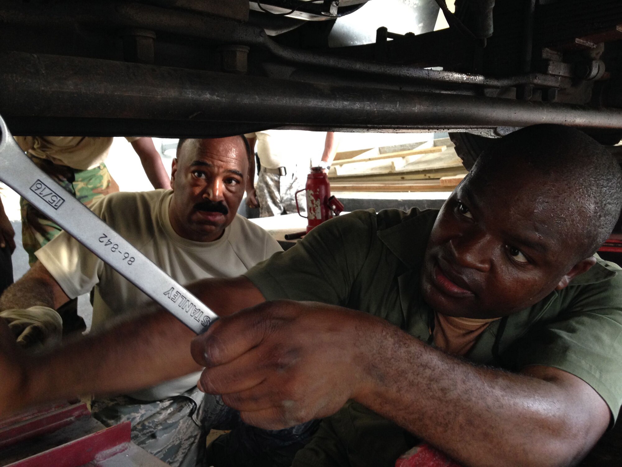 Senior Airman Renardo Butler (left) observes as Jamaican Defence Force civilian mechanic Lance Corporal Newland J. works on aligning a wheel on a 2.5-ton Jamaican Defence Force freightload truck. Butler, a vehicle mechanic from the 113th Wing, D.C. Air National Guard at Joint Base Andrews, Md., and Kemp are participating in a subject matter expert exchange under the National Guard Bureau’s State Partnership Program. (U.S. Air National Guard photo by Capt. Renee Lee)