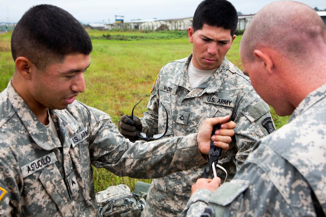 From left, U.S. Army  Cpl. Abraham Astudillo, U.S. Army  Pfc. Ignacio Madrid and U.S. Army  Pfc. William Stooksbury put on eye protection prior to a slingload operation at Robert International Airport in Monrovia, Liberia, Dec. 12, 2014. Astudillo, Madrid and Stooksbury are parachute riggers assigned to the 372nd Inland Cargo Transportation Company.