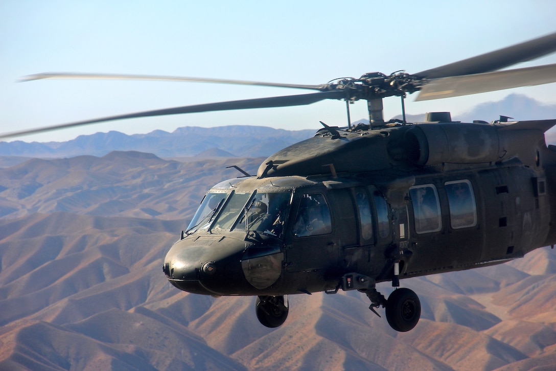 A UH-60 Black Hawk helicopter flies high over the rugged mountains of ...