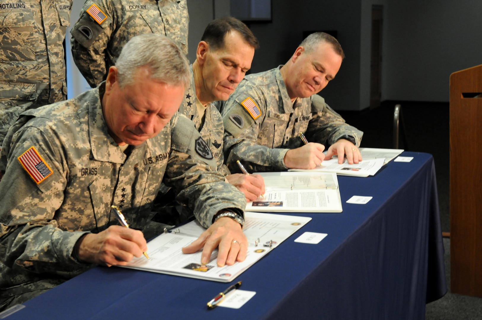 Army Gen. Frank J. Grass, chief of the National Guard Bureau, Air Force Lt. Gen. Stanley E. Clarke III, director of the Air National Guard, and Army Maj. Gen. Judd H. Lyons, acting director of the Army National Guard, sign the National Guard Bureau Diversity Strategic Plan at the Combat Readiness Training Center in Savannah, Georgia, Dec. 10, 2014. 