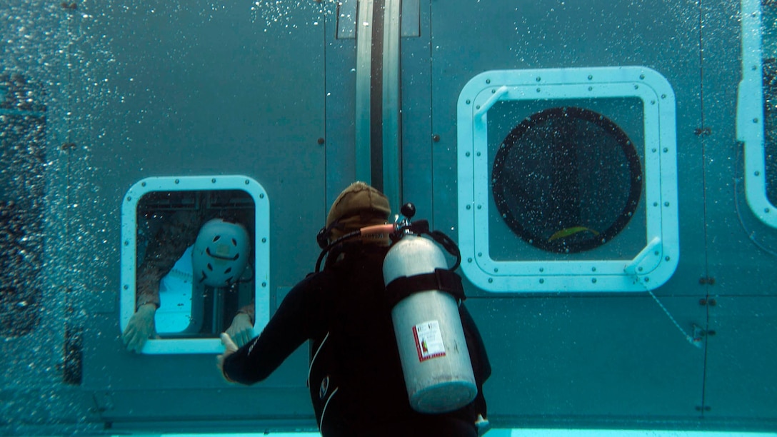 An underwater egress instructor oversees a Marine’s exit from a Modular Amphibious Egress Trainer during Underwater Egress Training Dec. 9 at the Hansen Aquatics Center. The Marines conducting the training are with Combat Logistics Battalion 31, 31st Marine Expeditionary Unit, and they are conducting pre-deployment preparations for the regularly-scheduled Spring Patrol of the Asia-Pacific region. 