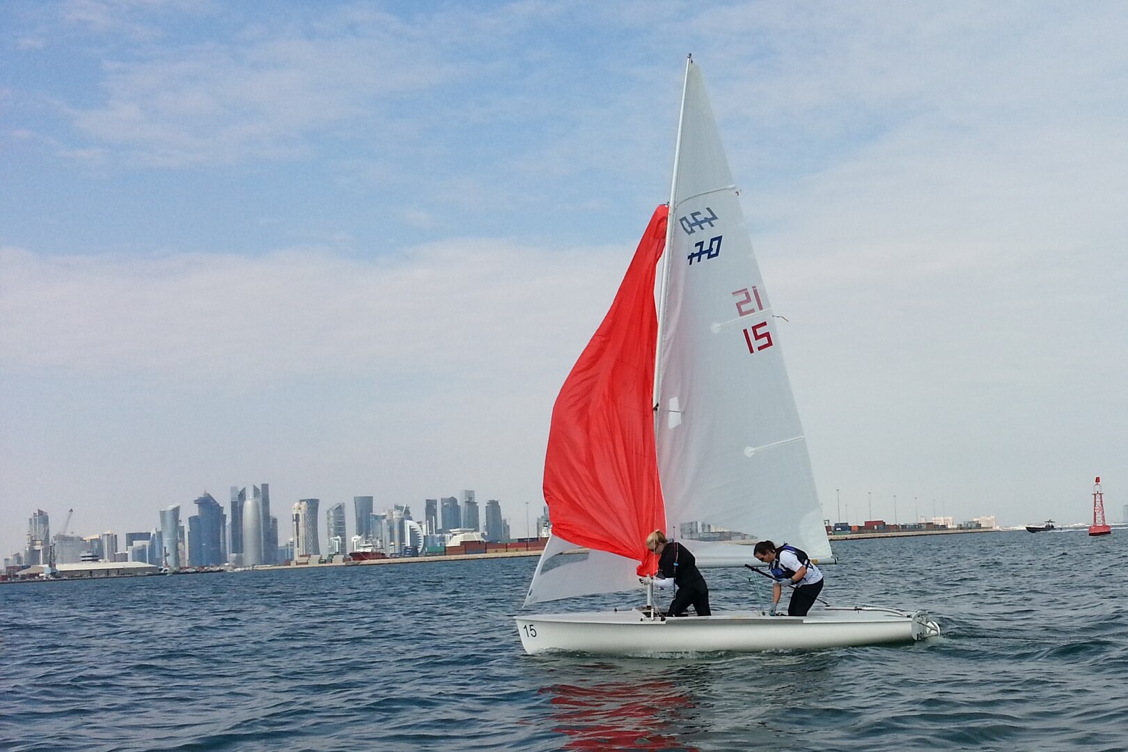 Women’s skipper Navy Lt. Trisha Kutkiewicz of Washington, D.C. and Air Force 2nd lt. Keisha Pearson of Joint Base Langley-Eustis, Va. at work on the sea with the Doha city skyline in the background during the 47th CISM World Military Sailing Championship held in Doha, Qatar Nov. 22-29, 2015.