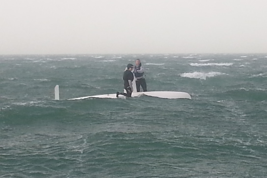 Women’s skipper Navy Lt. Trisha Kutkiewicz of Washington, D.C. and Air Force 2nd lt. Keisha Pearson of Joint Base Langley-Eustis, Va. on top of their capsized vessel after a massive sand and rain storm rolled through from inland out to sea halting all competition during the 47th CISM World Military Sailing Championship held in Doha, Qatar Nov. 22-29, 2015.