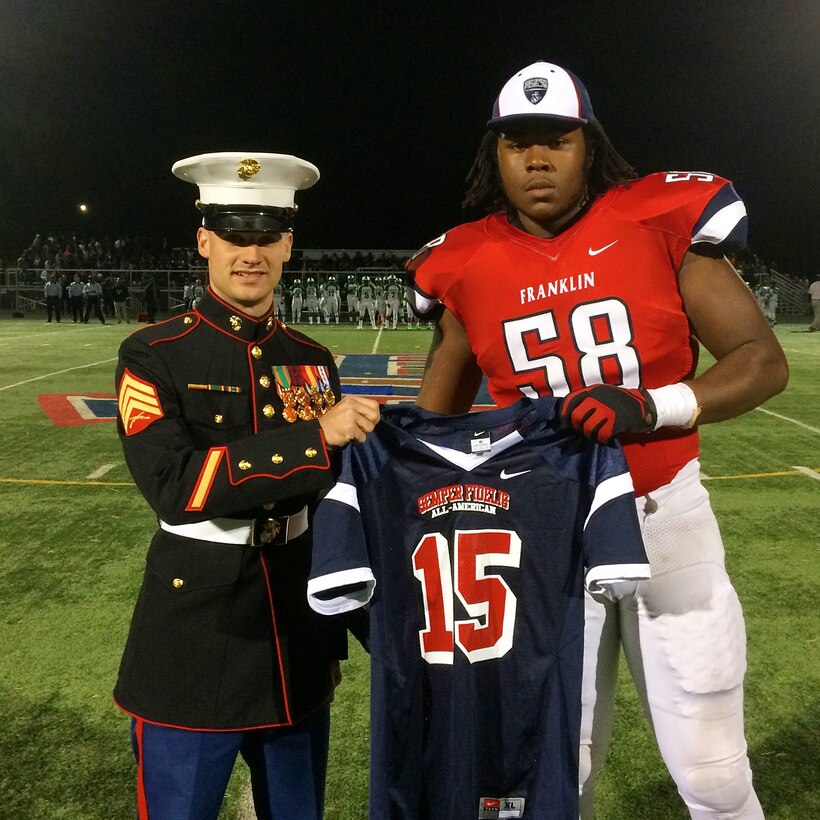 U.S. Marine Sgt. Evan A. Page, a recruiter with Marine Corps Recruiting Station Baltimore, and a native of Baltimore, presents a jersey to Patrick Allen at Franklin High School in Reisterstown, Maryland, October 24. Allen, an offensive tackle for Franklin High's football team, has been selected to play in the 2015 Semper Fidelis All-American Bowl, which will be played in Carson, California in January. (U.S. Marine Corps photo by Sgt. Bryan Nygaard/Released)