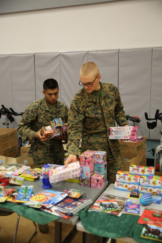 Pfc. Lucio Estrada and Pfc. Austin Larrabee, students, Marine Corps Communication-Electronics School, set up toy displays during Operation Homefront’s holiday distribution at the Community Center, Dec. 3, 2014. OHF hosts several events throughout the year, including a recognition event for an extraordinary military child. (Official Marine Corps photo by Lance Cpl. Medina Ayala-Lo/Released)