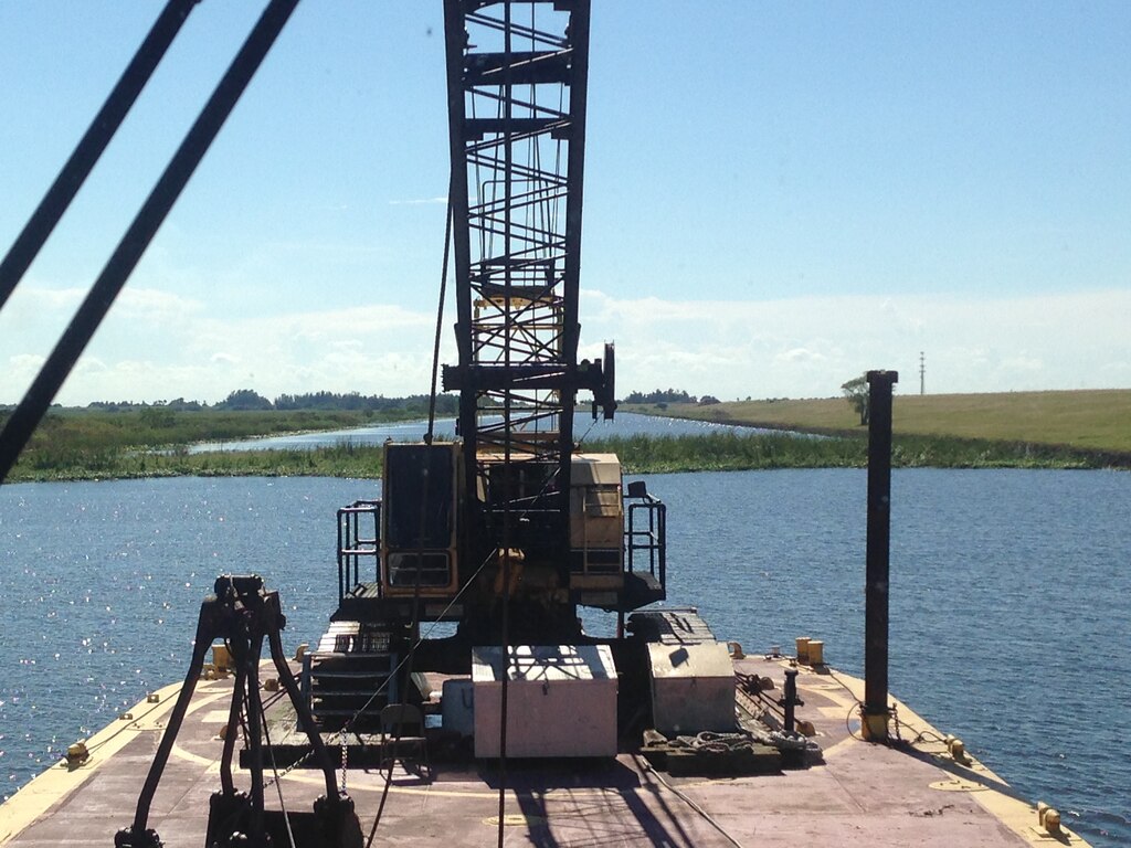 The tug boat Leitner pushed a barge mounted crane into position so a crew could break up and remove a half-acre tussock or floating island, restoring navigation along the Rim Canal Route 2 of the Okeechobee Waterway and the south side of Lake Okeechobee.