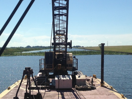 The tug boat Leitner pushed a barge mounted crane into position so a crew could break up and remove a half-acre tussock or floating island, restoring navigation along the Rim Canal Route 2 of the Okeechobee Waterway and the south side of Lake Okeechobee.