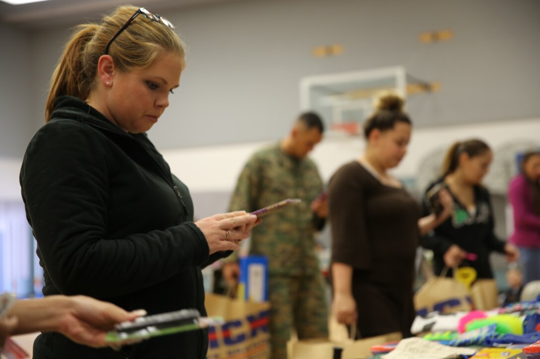 Rebecca Cade, military spouse, flips through a book during Operation Homefront’s holiday distribution at the Community Center, Dec. 3, 2014. OHF hosts a back to school brigade in the summer and holiday parties in November and December. (Official Marine Corps photo by Lance Cpl. Medina Ayala-Lo/Released)