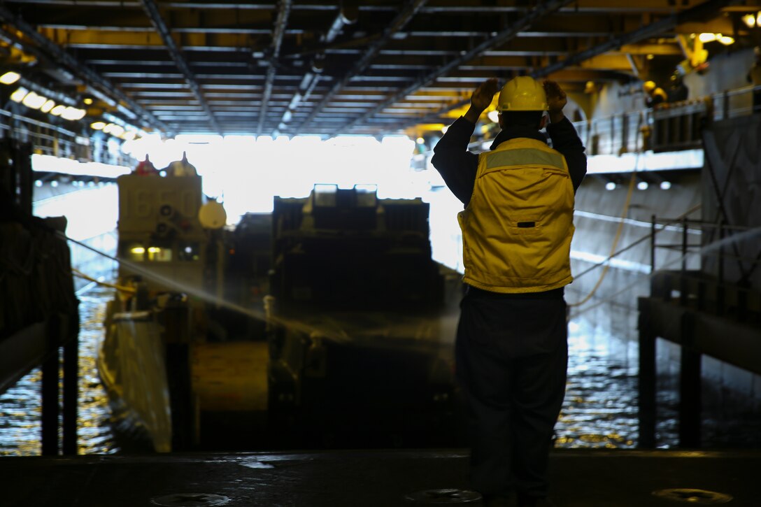 Seaman Michael Cundiff, a boatswain’s mate with the USS Iwo Jima, navigates a Medium Tactical Vehicle Replacement, or MTVR 7-ton, onto the ship, Dec. 14, 2014. The 24th MEU embarked on the ships of the Iwo Jima Amphibious Ready Group for their 2015 deployment Dec. 12-14. The 24th MEU is scheduled to support operations in the 5th and 6th Fleet areas of responsibility.