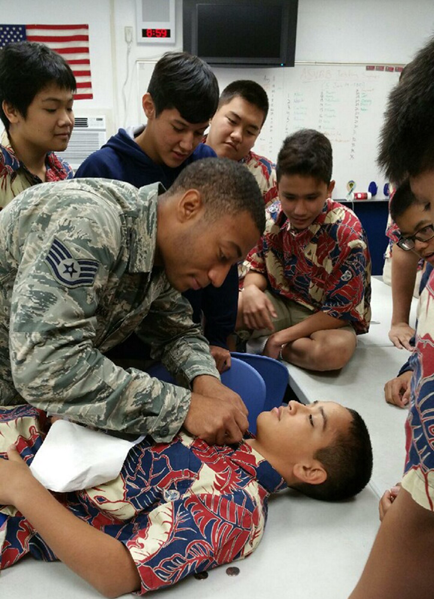 Staff Sgt. Justin Stinson, 15th Medical Operations Squadron, practices a medical technique on a St. Louis School Army Junior Reserve Officer Training Corps cadet during a lesson Dec. 5, 2014, in Honolulu, Hawaii. Stinson and other 15th Medical Group education and training flight members visit the JROTC cadets at least once a month to provide them basic medical and health training. (U. S. Air Force photo by Staff Sgt. Tamia Griffie/Released)