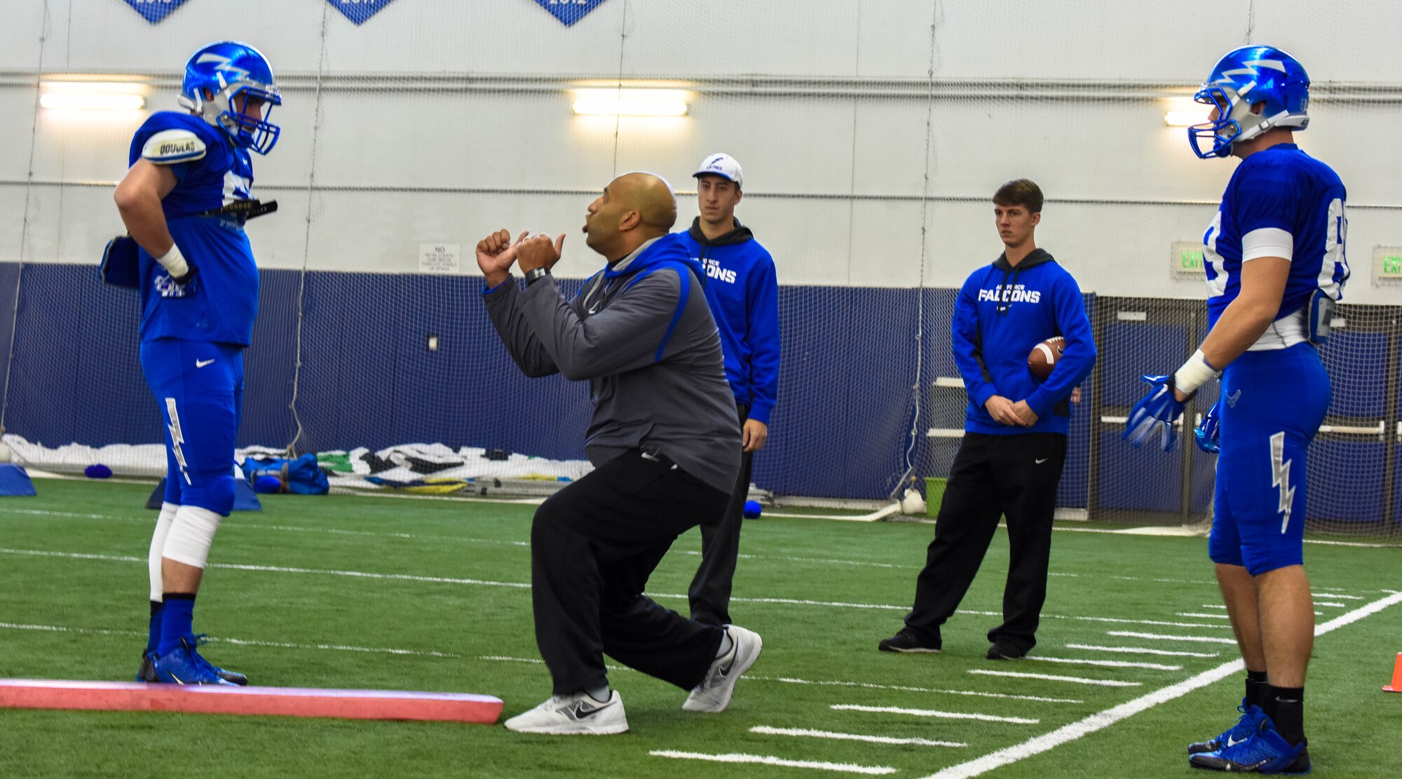 An Air Force Falcon coach performs proper blocking technique during practice Dec. 17, 2014, at the Caven Williams Sports Complex in Boise, Idaho. Players and coaches are preparing for the Famous Idaho Potato Bowl Dec 20, against the Western Michigan Broncos. (U.S. Air Force photo by Airman 1st Class Jeremy L. Mosier/RELEASED)