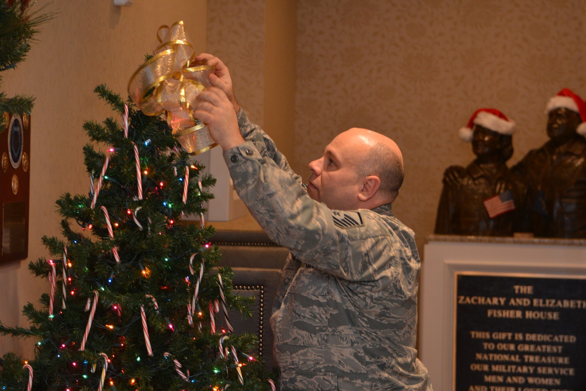 Master Sgt. Thomas Batchelor, 477th OSF, decorates a holiday tree in the foyer of the Alaska Fisher House on Joint Base Elmendorf Richardson, Alaska. The Fisher House serves patients and families from all branches of the military receiving active medical treatment at the base hospital or local area hospitals (U.S. Air Force Photo/Tech. Sgt. Dana Rosso)