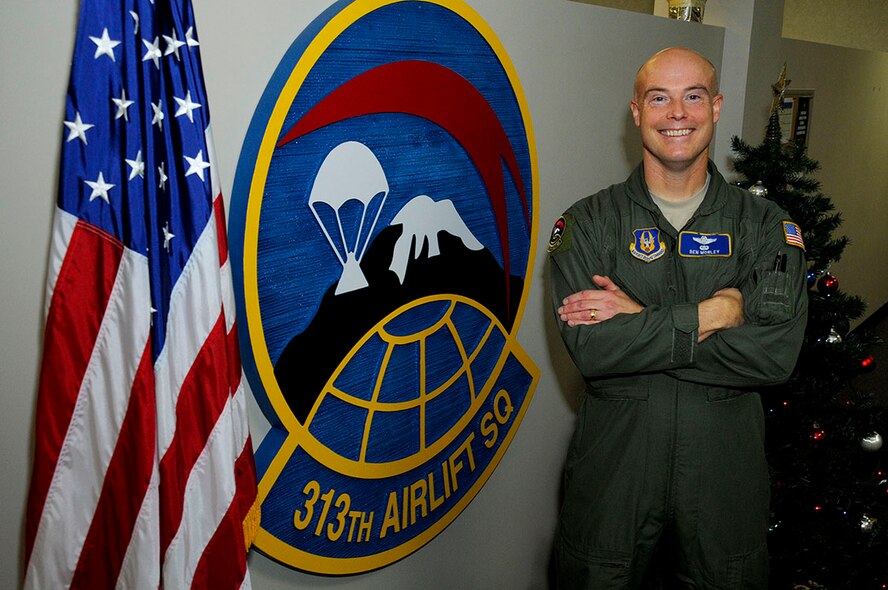 Lt. Col. Ben Morley, 313th Airlift Squadron air reserve technician and assistant operations manager, smiles for a photo next to his squadron’s emblem at McChord Field, Washington, Dec. 17, 2014. Morley recently returned from a temporary duty assignment as the stage manager at Joint Base Pearl Harbor-Hickam, Hawaii where he had the job of managing the logistics for presidential missions to and from Australia, Burma, and China. (U.S. Air Force Reserve photo by Senior Airman Madelyn McCullough)