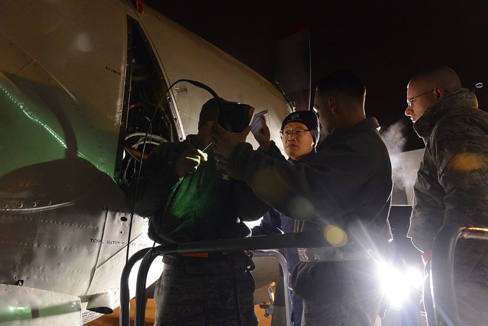 Air Force Staff Sgt. Alex O'Donnell, Master Sgt. Christopher Baldwin and Tech. Sgt. Matthew Summers of the 3rd Maintenance Squadron at Joint Base Elemendorf-Richardson consult with Senior Chief Petty Officer Shim Min Seok from South Korea navy Patrol Airgroup 61 during repair work to a South Korean P3 Orion aircraft at JBER, ALaska, Dec. 9, 2014. Members of Patrol Airgroup 61 partnered with Coast Guard and Air Force personnel at JBER to conduct a search for crewmembers missing from the sinking of the fishing vessel 501 Oryong. U.S. Coast Guard photo by Petty Officer 1st Class Shawn Eggert.