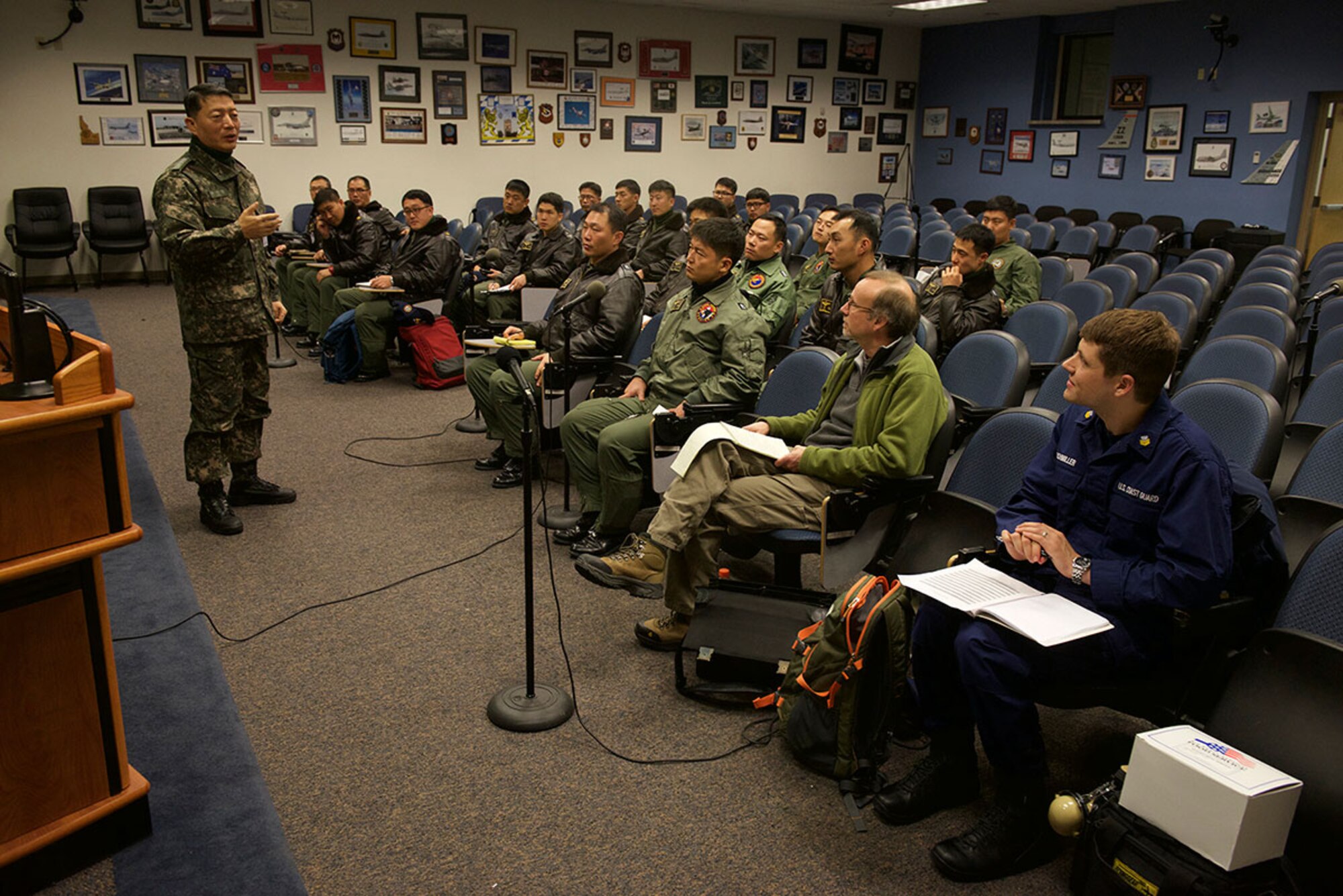South Korea navy Capt. Lee Jin-yong of Patrol Airgroup 61 addresses members of his airgroup as well as Ray Dwyer and Coast Guard Petty Officer 1st Class Jared Buchmiller from the 17th District command center in Juneau, Alaska, during a debrief at Joint Base Elmendorf-Richardson Dec. 8, 2014. U.S. Coast Guard and Air Force personnel assisted the Republic of Korea in their search for crewmembers from the fising vessel 501 Oryong when it sank in the Bering Sea Dec. 1. U.S. Coast Guard photo by Petty Officer 1st Class Shawn Eggert.