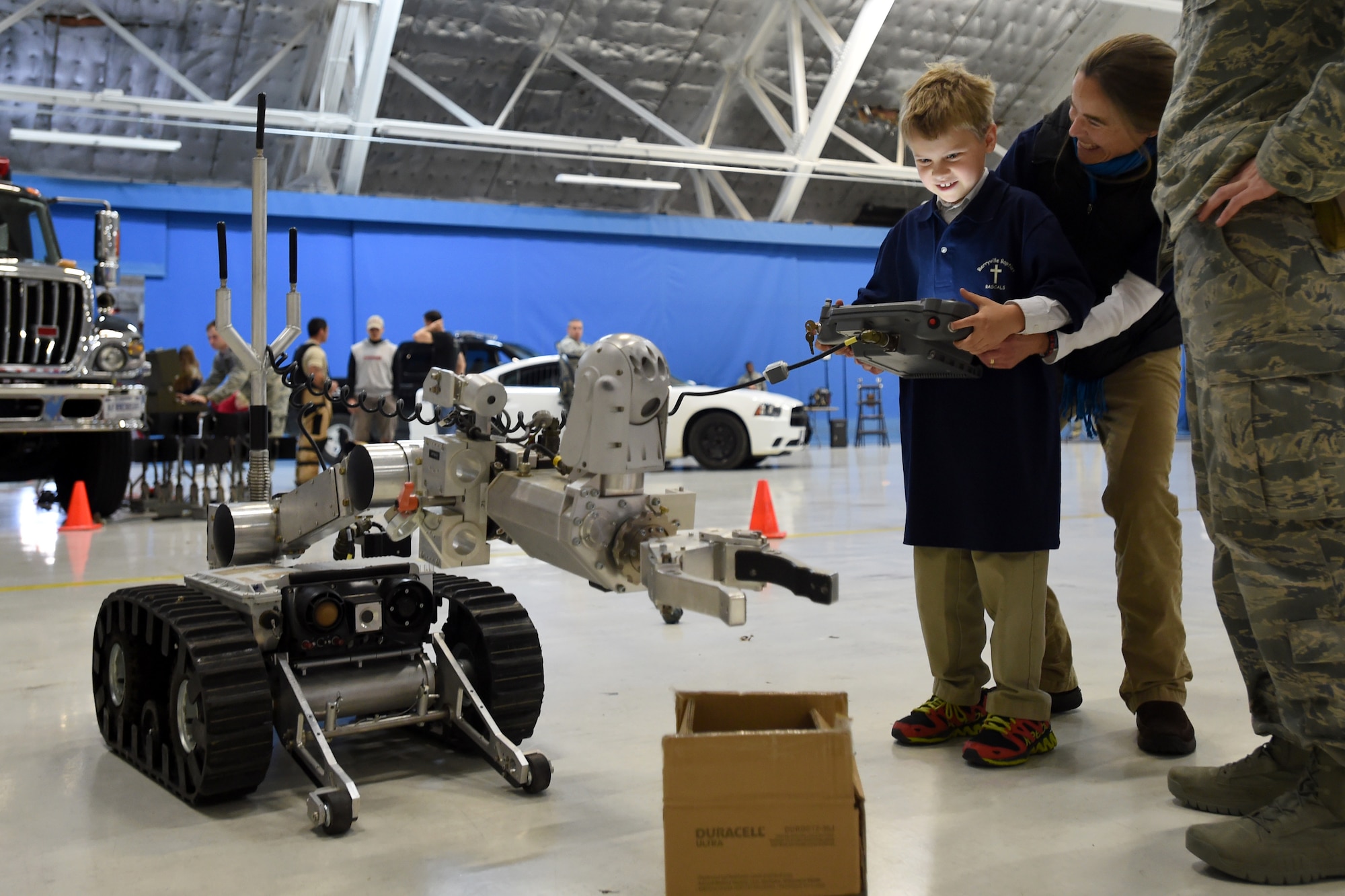 Jacob and his mother, Robin Coutts learn how to operate an Explosive Ordinance Disposal robot during the Parents and Children Fighting Cancer Holiday Party on Joint Base Andrews, Md., Dec. 13, 2014.  The Coutts volunteered with The Berryville Baptist Rascals to put on a puppet show for the families. (U.S. Air Force photo/ Senior Airman Nesha Humes)