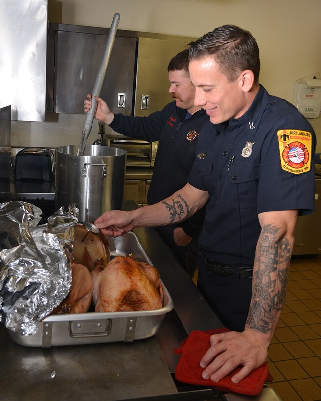 Roc Sweeney stirs a pot of posole as Matt Wood checks the internal temperature of a turkey. The firefighters and many others on base helped prepare food for Operation Holiday Cheer. (Photo by Todd Berenger)