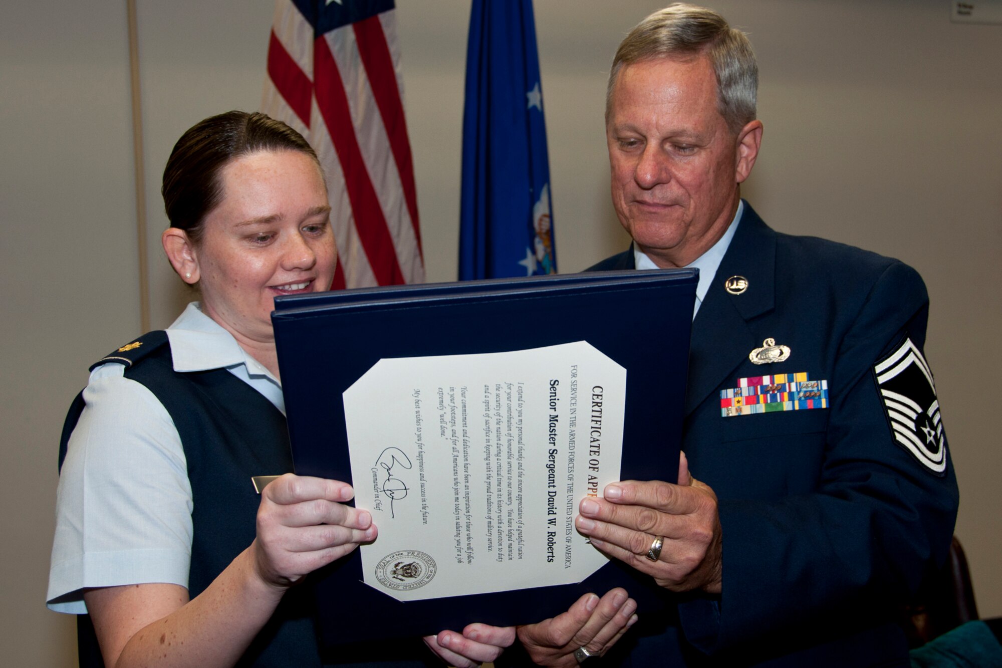 U.S. Air Force Major Stephanie Kennedy, 307th Force Support Squadron operations officer, reads the retirement certificate with Senior Master Sgt. David Roberts, 307th FSS Education and Training superintendent, during his retirement ceremony Dec. 6, 2014, at Barksdale Air Force Base, La. Roberts is retiring after 39 years of military service. (U.S. Air Force photo by Master Sgt. Mary Hinson/Released)