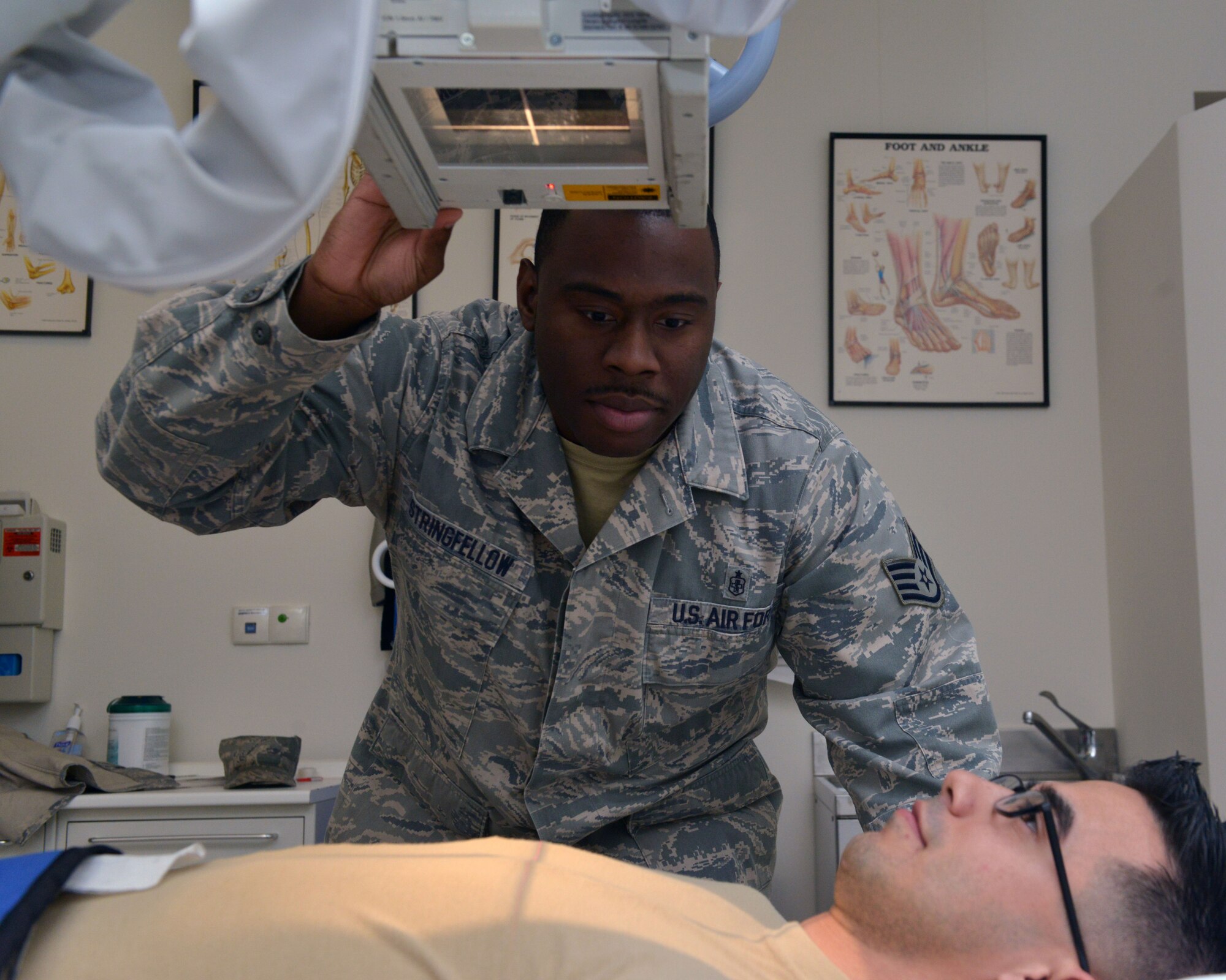 Staff Sgt. Job Stringfellow, 31st Surgical Operations Squadron radiologic technologist, prepares Senior Airman Gilberto Miramontes, 31st Medical Operations Squadron, for an x-ray, Dec. 16, 2014, at Aviano Air Base, Italy. Radiology technicians capture imagery to give an accurate representation of what’s going on in a patient’s body to help the doctor better diagnose physical problems. (U.S. Air Force photo/Airman 1st Class Ryan Conroy)   