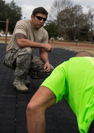 Technical Sgt. Ismael Villegas, a combat controller who is a two-time Silver Star recipient and an Air Force Special Operations Command in-service recruiter, coaches Staff Sgt. Robert Gallagher’s as he does push-ups during a practice Physical Ability and Stamina Test, Dec. 9, 2014, at Joint Base Charleston, S.C. Gallagher is a 560th Red Horse Squadron reservist who is in the process of becoming a combat controller. (U.S. Air Force photo/Senior Airman Jared Trimarchi) 