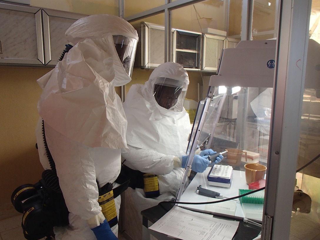 Technicians set up polymerase chain reaction, or PCR, assay for Ebola in a containment laboratory. Assay components are assembled in the PCR hood to prevent contamination that could interfere with test results. U.S. Army photo by Dr. Randal J. Schoepp