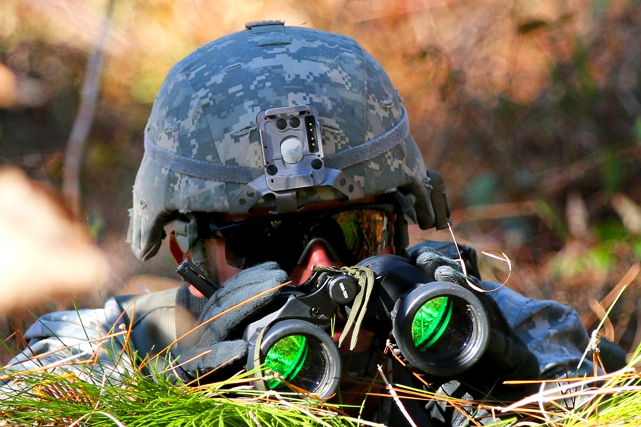 A soldier looks through binoculars at a simulated enemy target