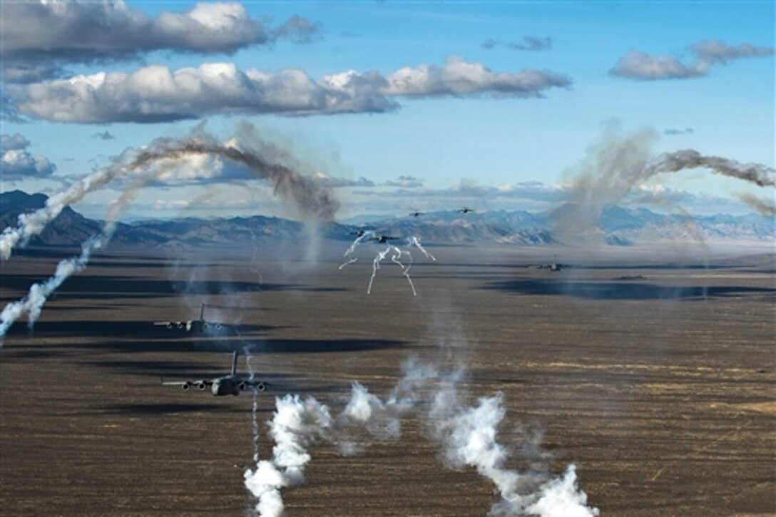C-17 Globemaster IIIs deploy flares during the U.S. Air Force Weapons School's Joint Forcible Entry Exercise 14B over the Nevada Test and Training Range on Nellis Air Force Base, Nev., Dec. 6, 2014. 