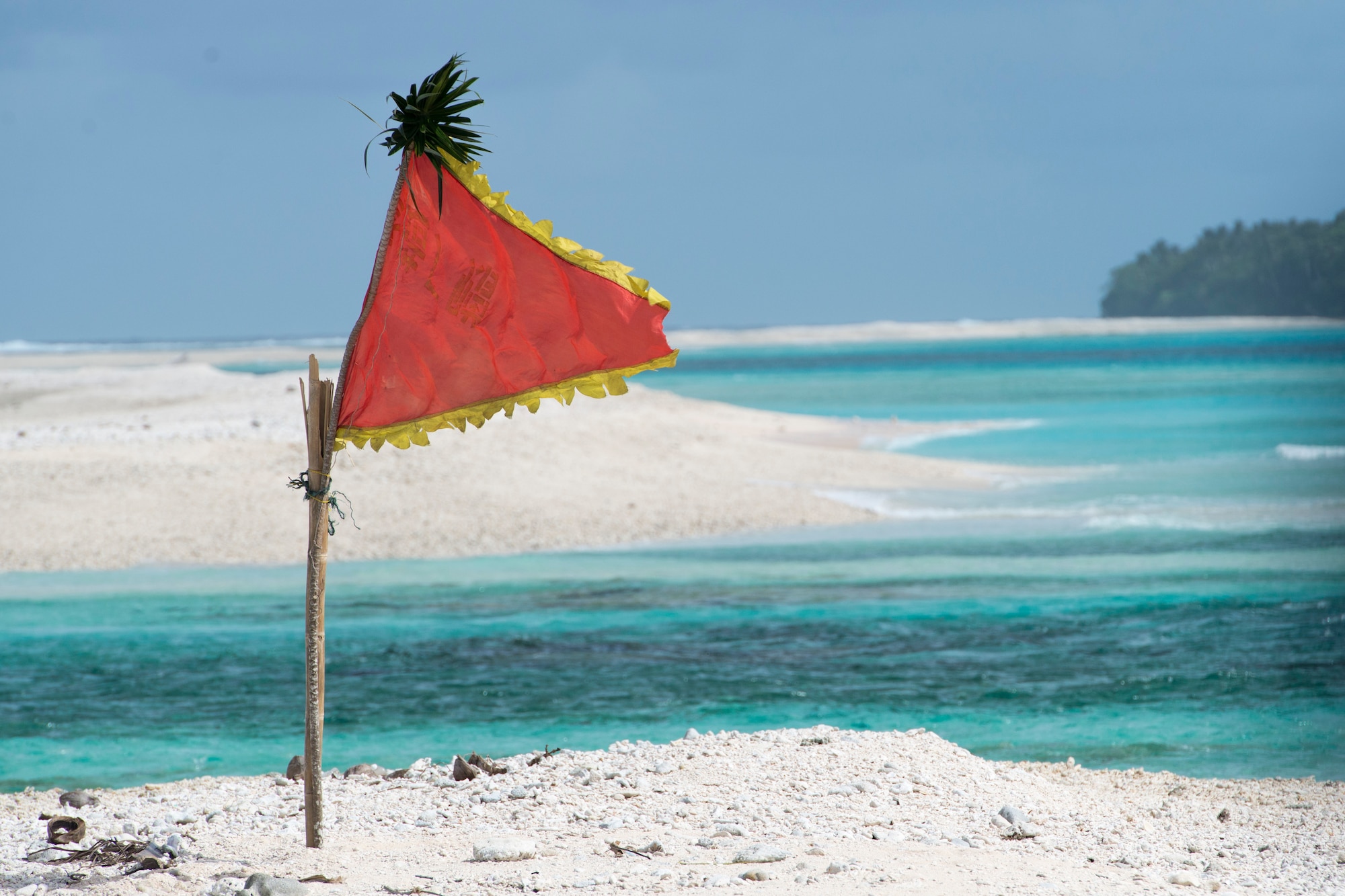 A flag flaps in the wind, marking a designated drop zone for Operation Christmas Drop packages Dec. 9, 2014, at Ulithi Atoll, Micronesia. The C-130 Hercules aircrew dropping the package flew upwind and dropped the package within sight of the flag. (U.S. Air Force photo/Staff Sgt. Cody H. Ramirez)