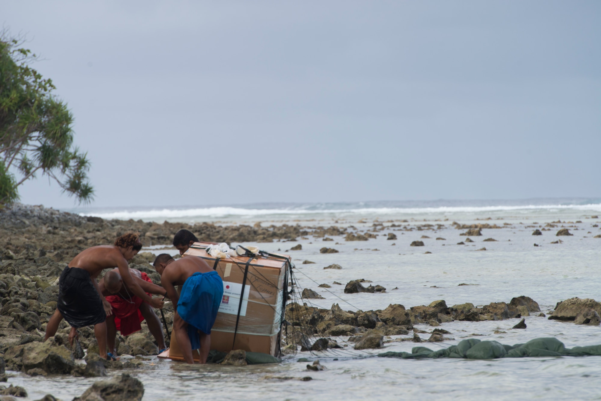 Islanders rush to lift a package out of the water during Operation Christmas Drop Dec. 9, 2014, at Ulithi Atoll, Micronesia. The bundle weighed 550 pounds, bringing food, clothes, tools and toys to the island in celebration of Christmas. This reminder of Christmas has been airdropped to the islands of Micronesia for 63 continuous years. (U.S. Air Force photo/Staff Sgt. Cody H. Ramirez)