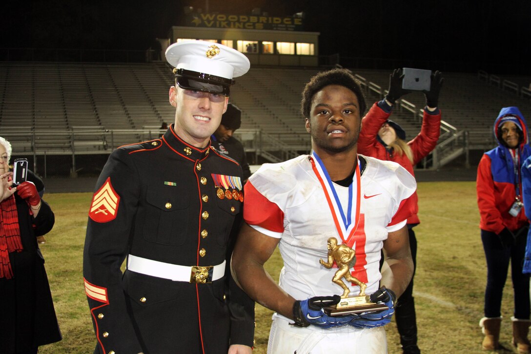 U.S. Marine Corps Sgt. Kyle G. Butzer, a recruiter with Recruiting Sub-Station Woodbridge, presented the Great American Rivalry Series Most Valuable Player award of the winning team between Woodbridge and Garfield during their annual rivalry game Nov. 7, 2014. The Great American Rivalry Series has been partnered with the US Marine Corps multiple times for this game rich in tradition. The away team Garfield tied late in the 3rd quarter and continued to push to take the win 35-21. (U.S. Marine Corps photo by Cpl. Amber Williams/Released)