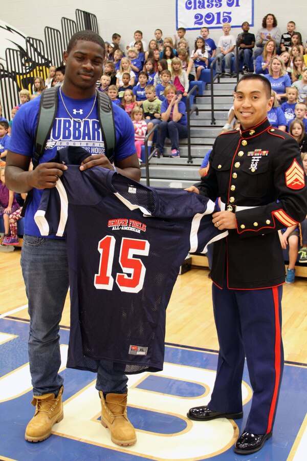 U.S. Marine Corps Sgt. Albert Opena III, a canvassing recruiter for Recruiting Sub-Station Tri-County, presented a commemorative jersey to Hubbard High School’s Larry “LJ” Scott for his selection to the Semper Fidelis All-American Bowl game Oct. 3, 2014, in Hubbard, Ohio. The Eagles’ star running back will represent the East Team during the bowl game that will which place January 4, 2015 at StubHub Center in Carson, California. (U.S. Marine Corps photo by Sgt. Timothy Stewmam/Released)