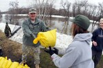 Army Maj. Gen. David Sprynczynatyk, the adjutant general of the North Dakota, passes a sandbag to a civilian flood fighting volunteer along the Red River in the south end of Fargo, N.D., March 16, 2010. The Guard is decreasing the number of Soldiers and Airmen on state active duty for the floods.