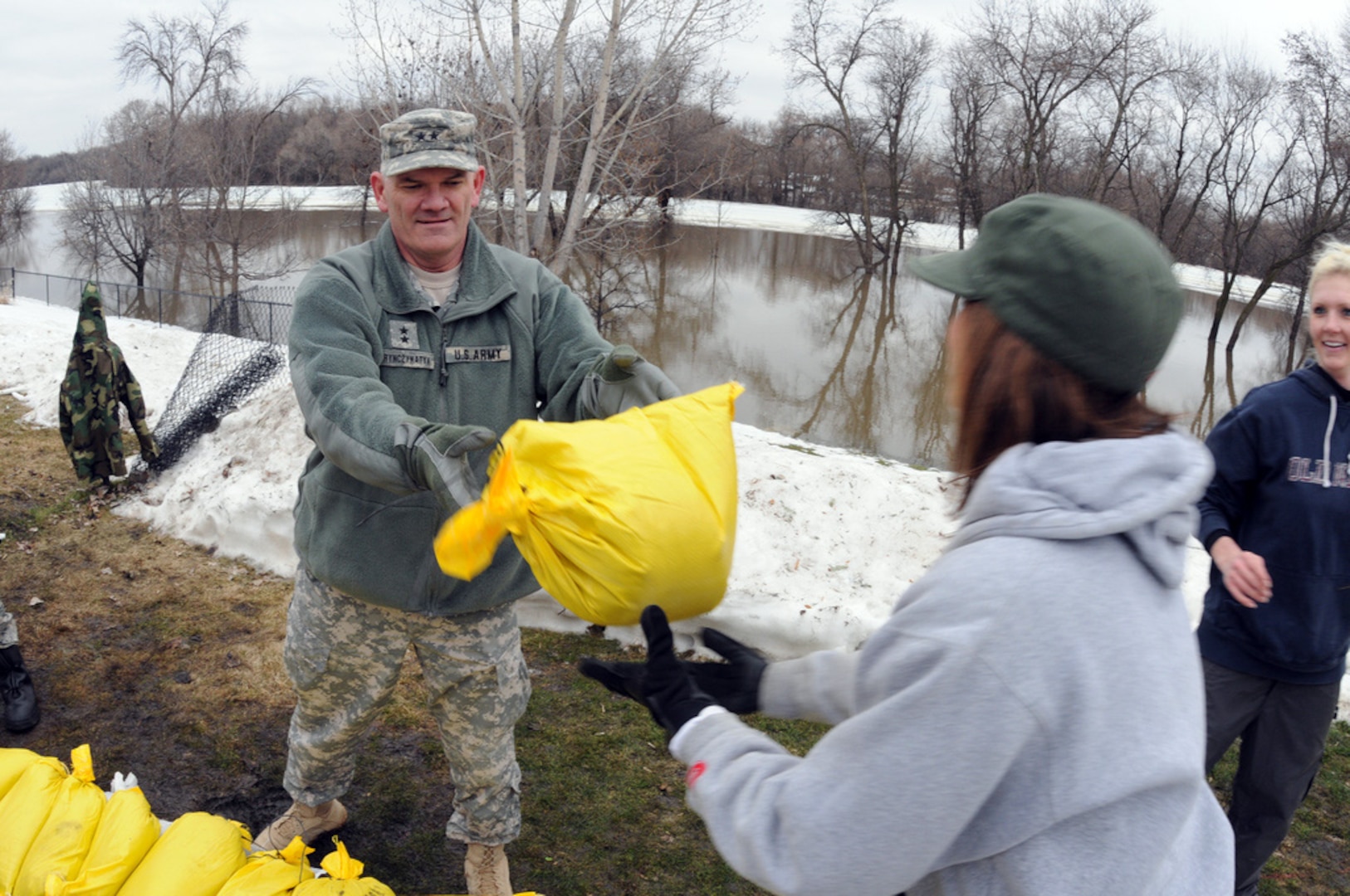 Army Maj. Gen. David Sprynczynatyk, the adjutant general of the North Dakota, passes a sandbag to a civilian flood fighting volunteer along the Red River in the south end of Fargo, N.D., March 16, 2010. The Guard is decreasing the number of Soldiers and Airmen on state active duty for the floods.