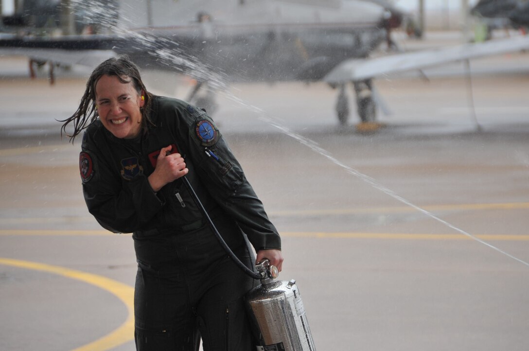 Lt. Col. Amy Young, 80th Flying Wing T-6 Texan II instructor, gets hosed down with water by family, friends and coworkers Dec. 18, 2014, at Sheppard Air Force Base, Texas, following the completion of her “fini-flight.” Fini-flights are a long-standing military aviator tradition honoring a pilot on their departure from an assignment or their retirement from the Air Force. (U.S. Air Force photo/Airman 1st Class Robert L. McIlrath)