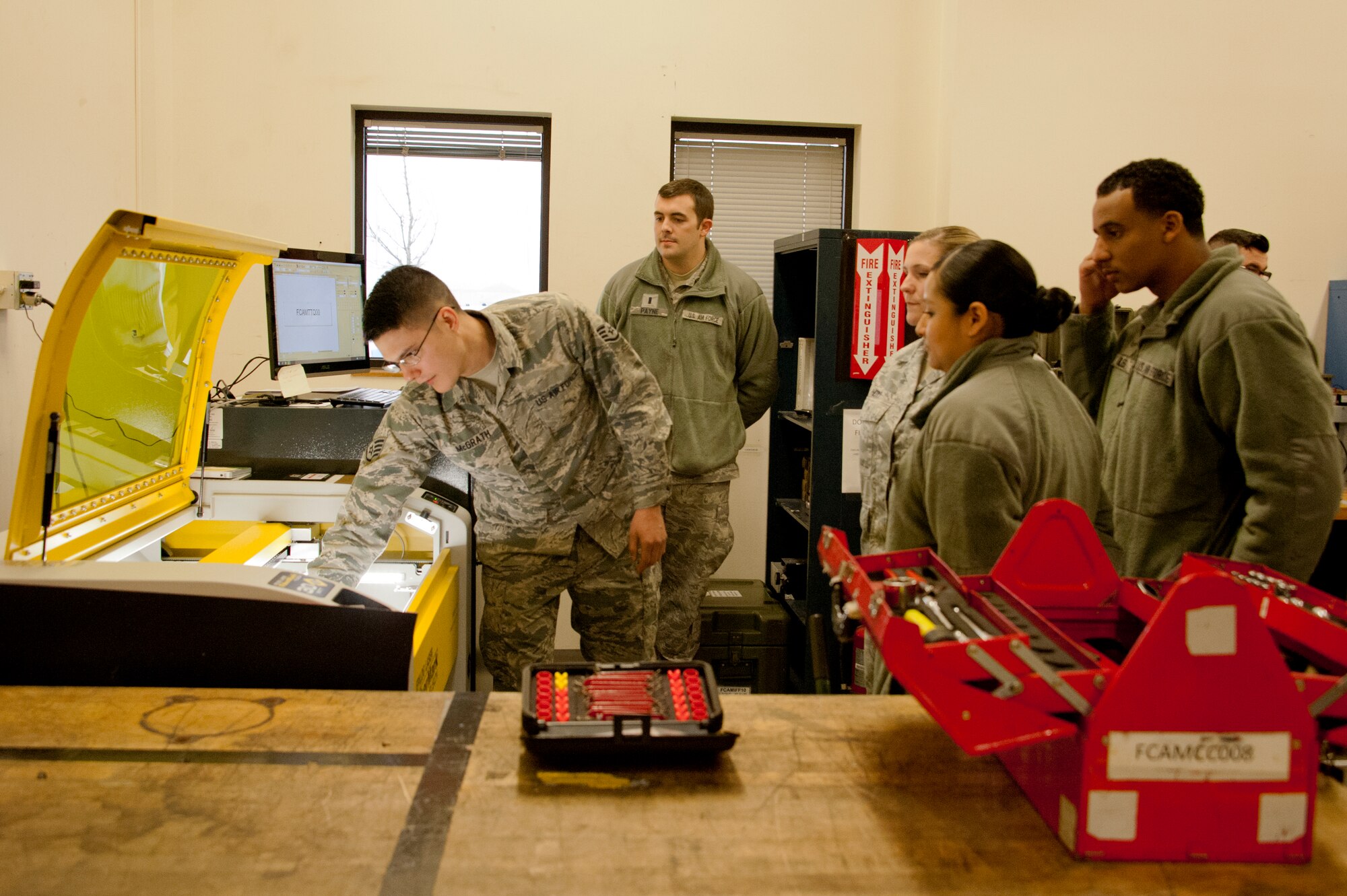 Staff Sgt. Dustin McGrath, 92nd Aircraft Maintenance Squadron sortie support specialist, shows the capabilities of the new laser etcher to members of the 92nd Contracting Squadron during a tour Dec. 5, 2014, at Fairchild Air Force Base, Wash. The goal of the tour was to increase the understanding of the maintenance mission and show the contracting personnel firsthand the important role they play by purchasing equipment that saves time, money, and manpower for the 92nd Maintenance Group. (U.S. Air Force photo/Airman 1st Class Nicolo J. Daniello)