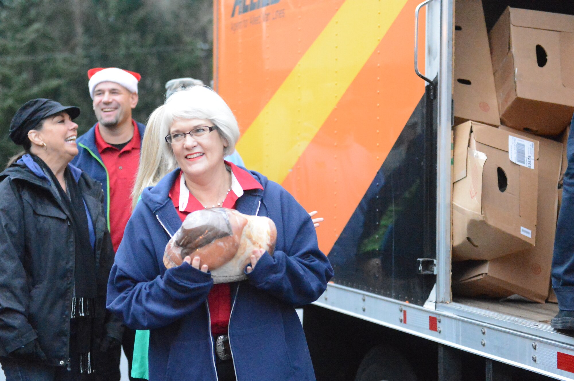 Patty Denny (center), from Fix Auto USA, delivers a Christmas ham to the 22nd Special Tactics Squadron Dec. 18, 2014,  as part of Operation Ham Grenade at Joint Base Lewis-McChord, Wash. The annual event, coordinated between community leaders and military-affiliated organizations, is currently in its fifth year of operation.  (U.S. AirForce photo/Senior Airman Rebecca Blossom)