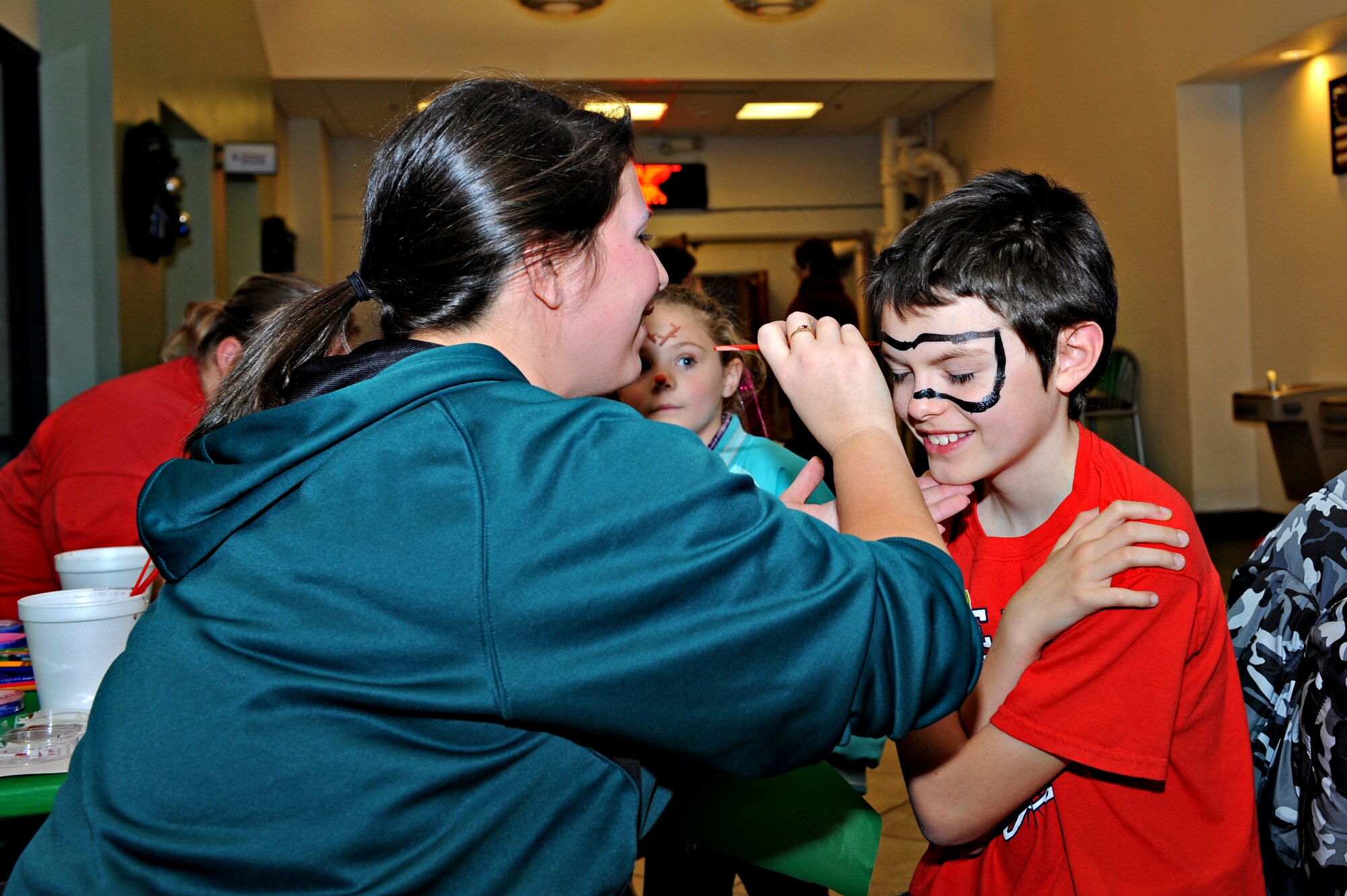 Volunteer members of Team Beale face paint during the Exceptional Family Member Program holiday party Dec. 17, 2014, at Beale Air Force Base, Calif. The EFMP is designed to provide support to family members, both adult and children with special needs such as a physical, developmental, or mental disorder requiring specialized services. (U.S Air Force photo by Airman 1st Class Ramon A. Adelan/Released)