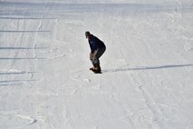 Airman 1st Class Mikal Joyce, 5th Maintenance Squadron, snowboards down a hill during military appreciation day at Bottineau Winter Park, Dec. 13, 2014. More than 170 Airmen and families were admitted into the park for free. (U.S. Air Force photo/2nd Lt. Kilee Ashton) 