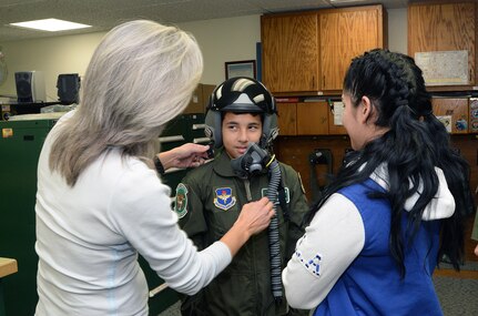 Darlene Daspit-Pohl, Aircraft Survival and Flight Equipment supervisor, helps Jorge Ortiz, a 10-year-old recovering from cancer, try on a flight helmet during his tour of the 560th Flying Training Squadron Dec. 17, 2014, at Joint Base San Antonio-Randolph. Ortiz participated in the 12th Flying Training Wing Pilot for a Day Program. The program offers local children with disabilities or serious illnesses a chance to enjoy a day totally focused on them and their interest in aviation. (U.S. Air Force photo by Johnny Saldivar)
